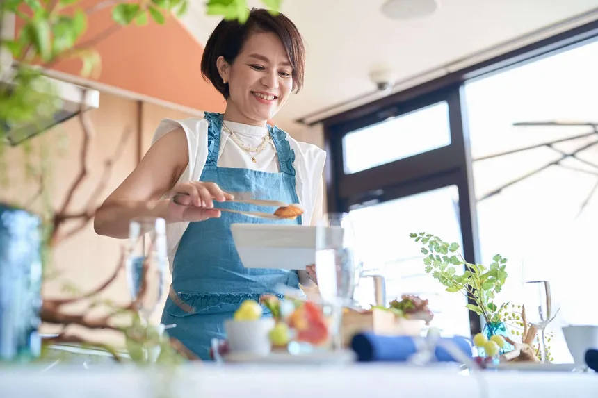 テーブルに料理を取り分けるエプロン姿の女性