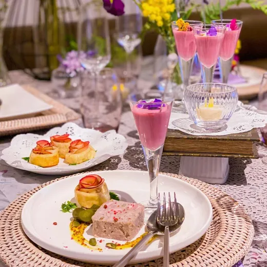 花を添えたピンクのドリンクと一口サイズの料理